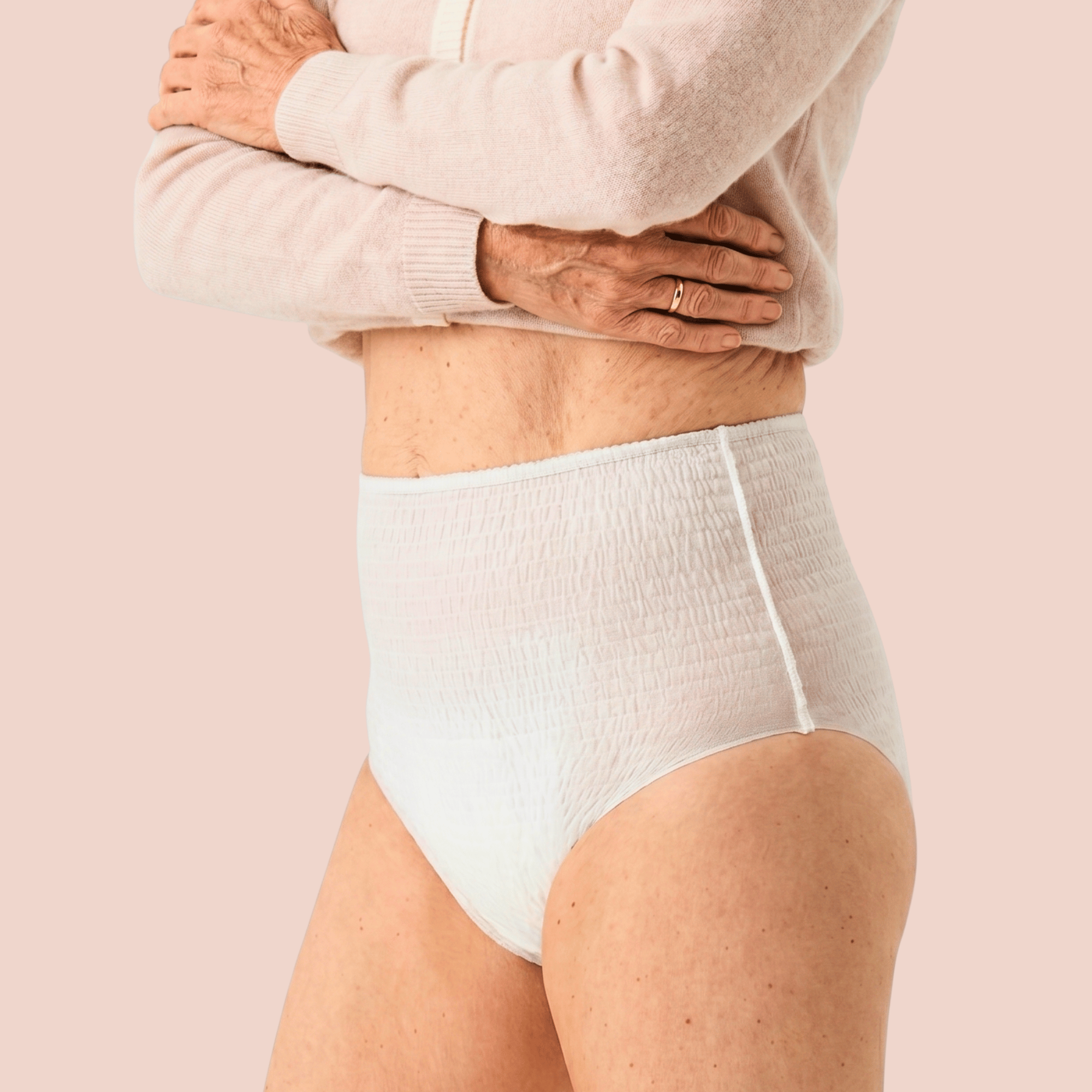 Femme portant une culotte d'incontinence absorbante blanche à taille haute, vue de trois-quart sur fond rose pâle.